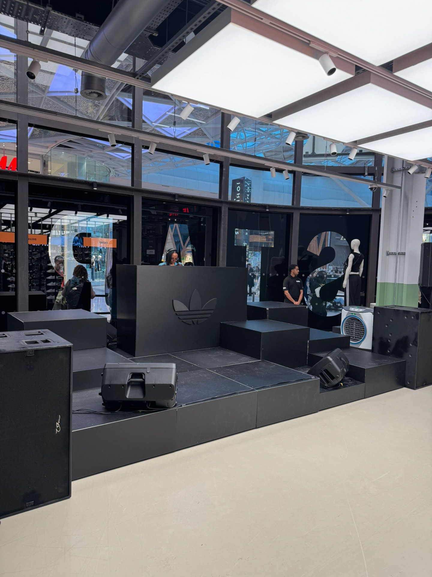 Stage build with DJ booth, monitors and cooling fan in a mall atrium